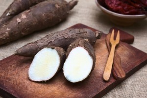 Cut manioc halves (lat. Manihot esculenta) on wooden board photographed with natural light (Selective Focus, Focus on the cut maniocs)